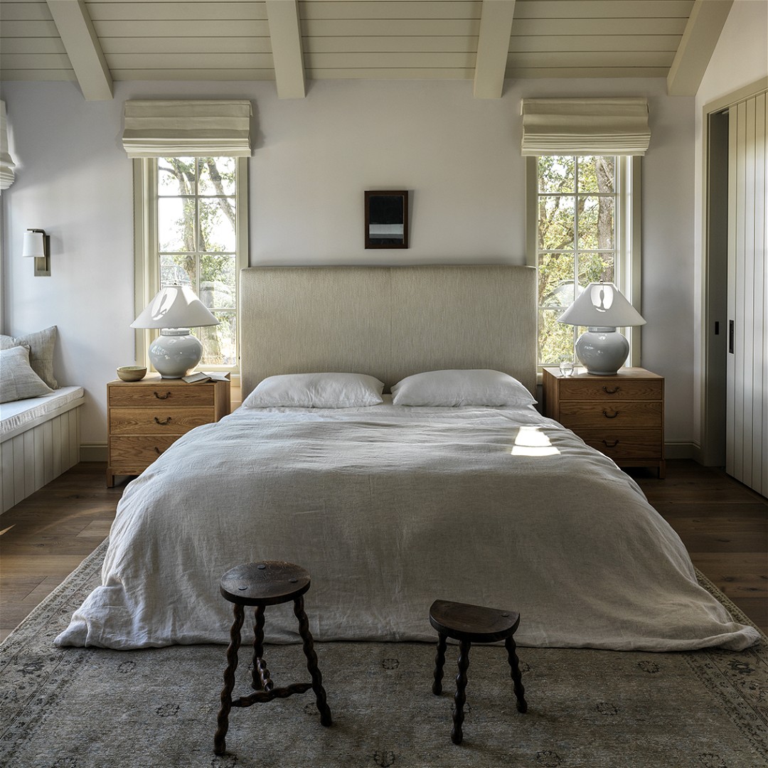 a bedroom with a large bed and two stools
