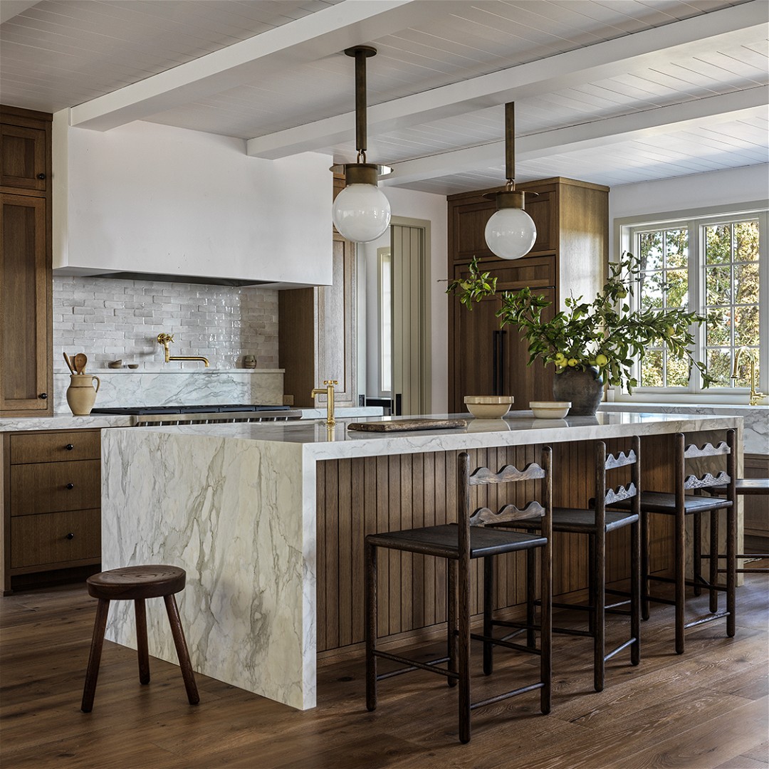 a kitchen with a marble island and wooden cabinets