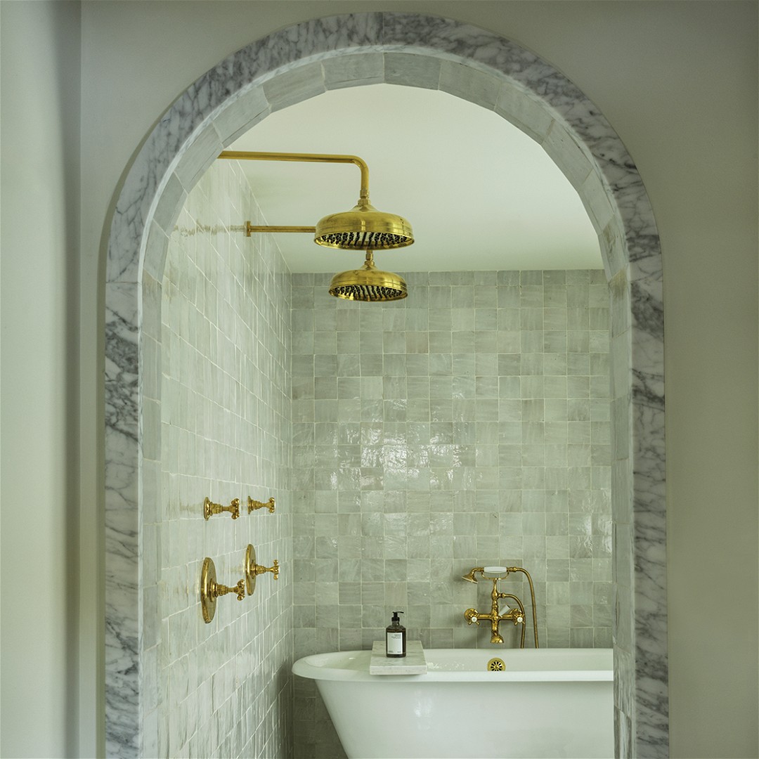 a white bath tub sitting under a golden faucet