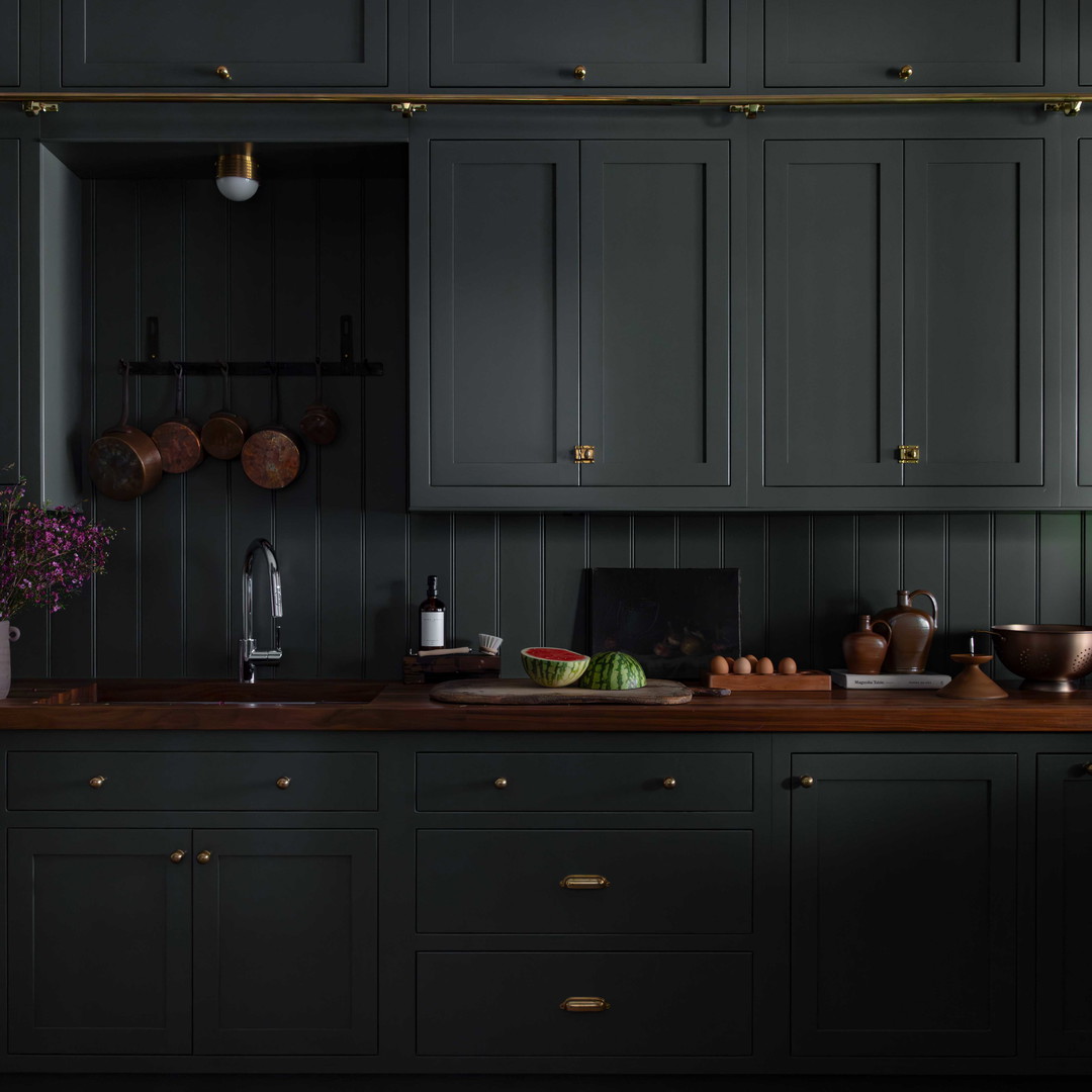 a kitchen with dark green cabinets and wooden counter tops