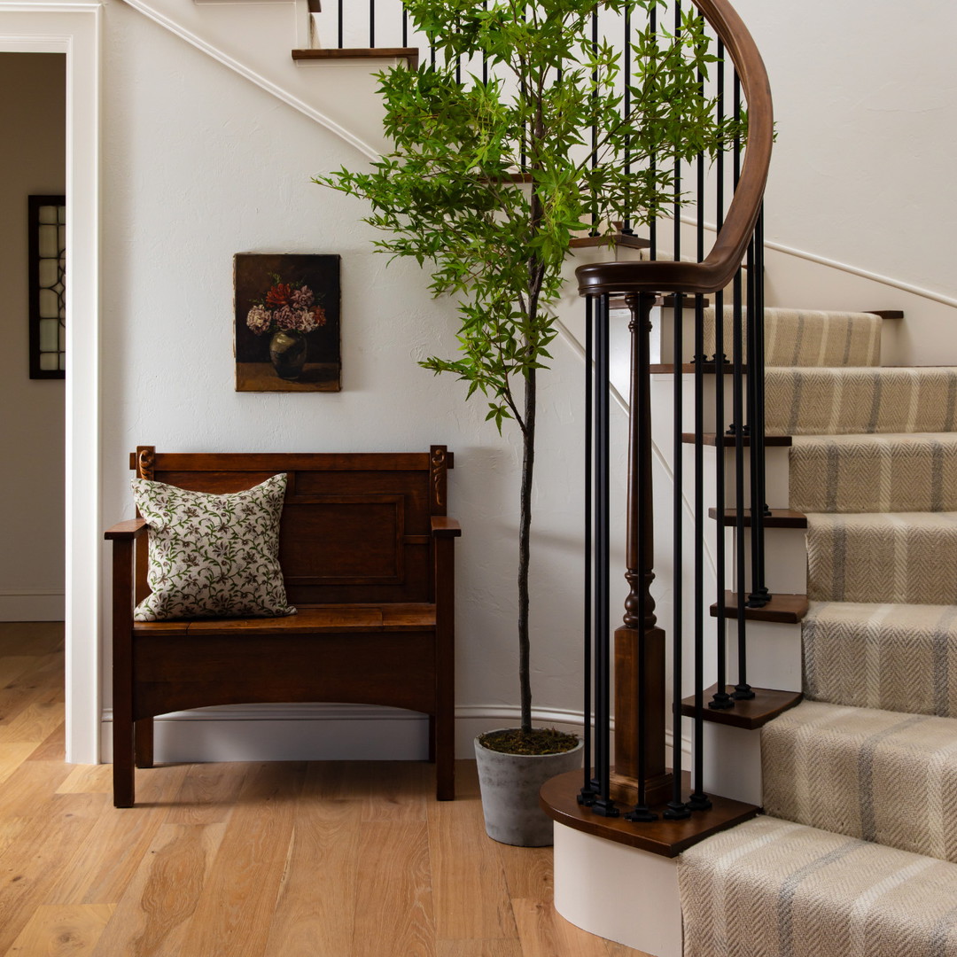 a wooden bench sitting under a stair case next to a tree