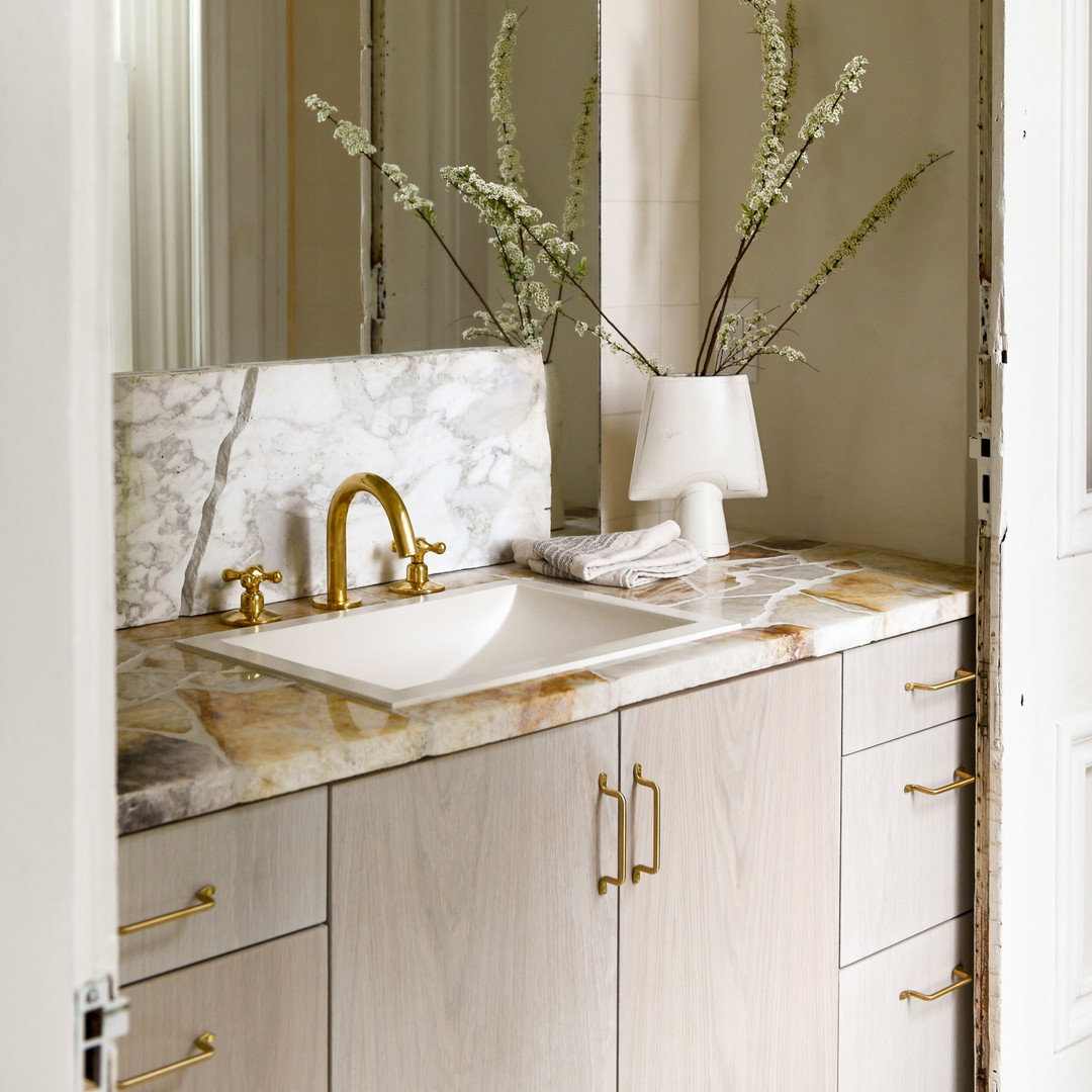 a bathroom with a marble counter top and a gold faucet