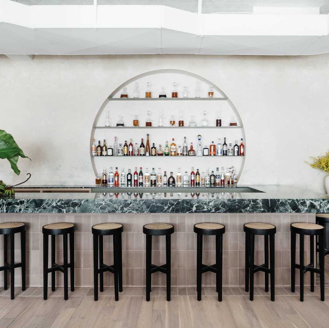 a bar with stools and bottles on the wall