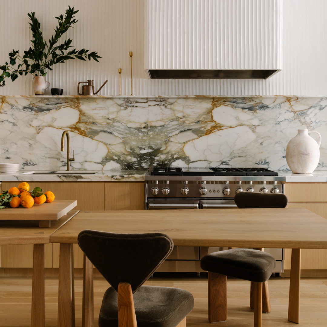 a kitchen with a marble counter top and wooden chairs