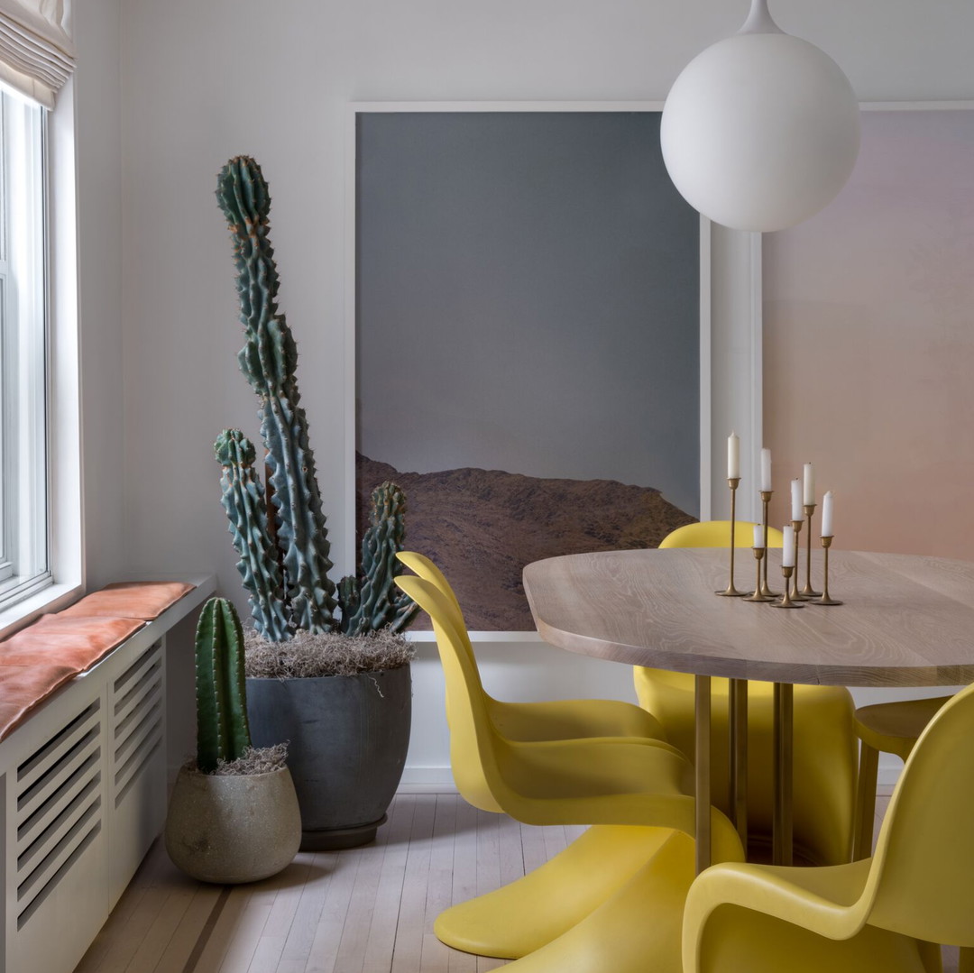 a dining room table with yellow chairs and a cactus