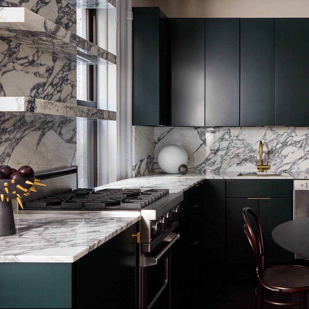 a kitchen with marble counter tops and black cabinets