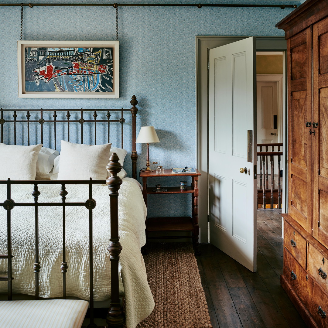 a bedroom with a bed, dresser and a painting on the wall