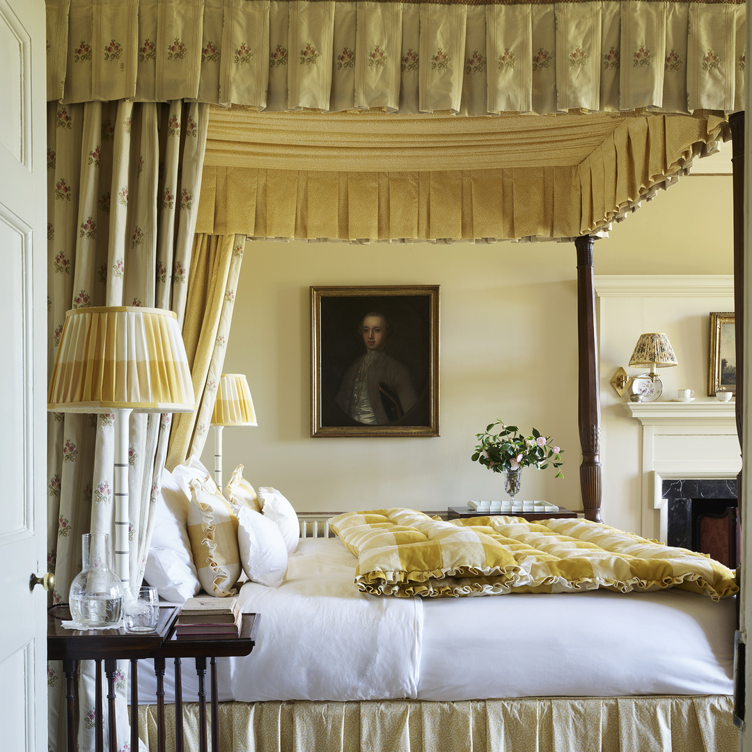 a bedroom with a canopy bed and a painting on the wall