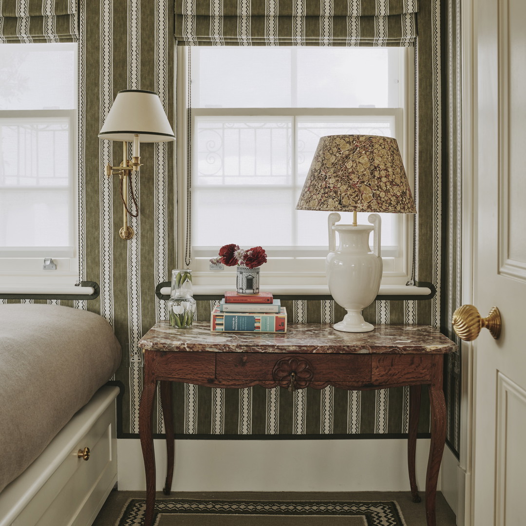 a bedroom with a bed and a table with a lamp on top of it