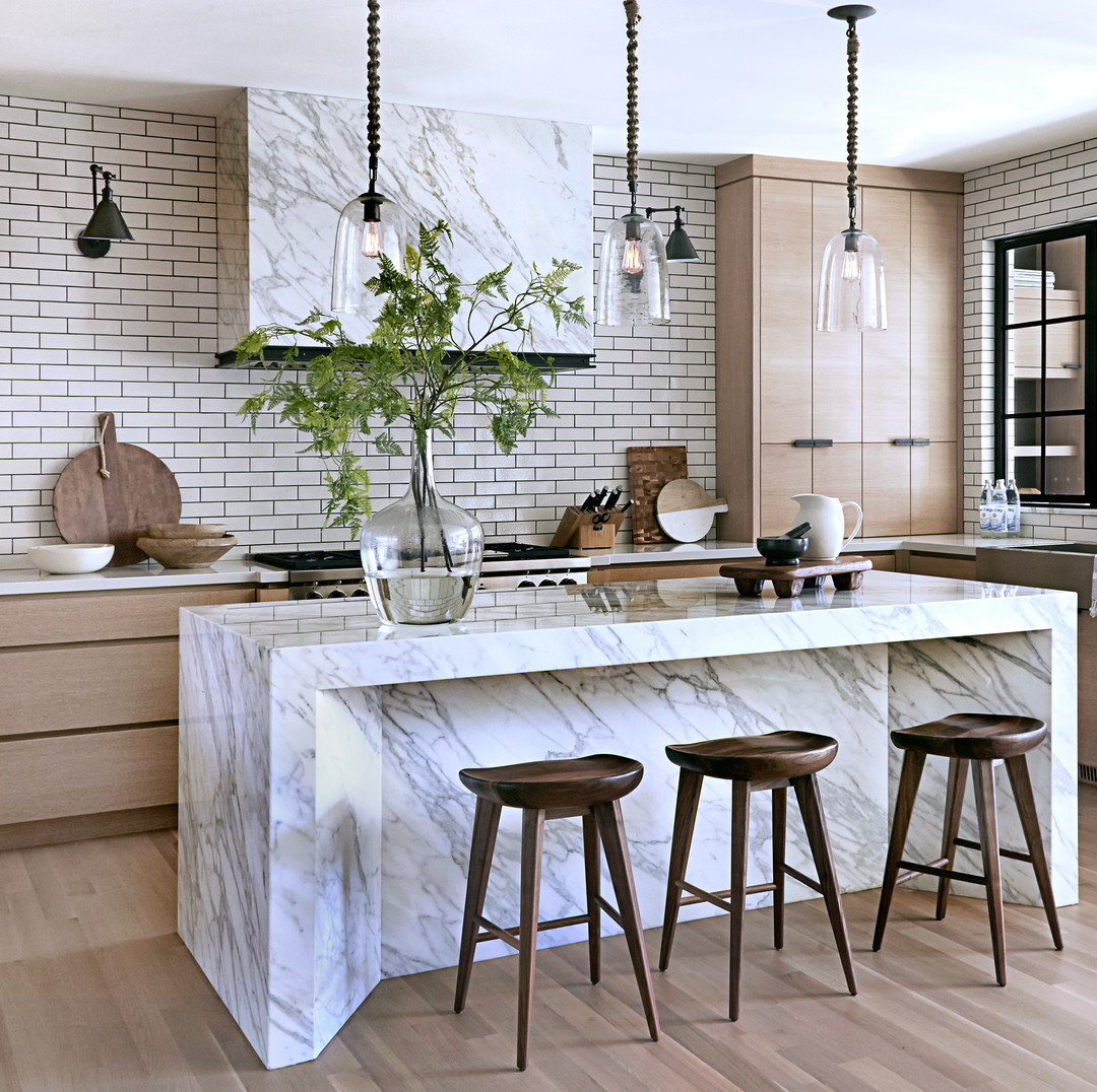 a kitchen with a marble island and wooden stools