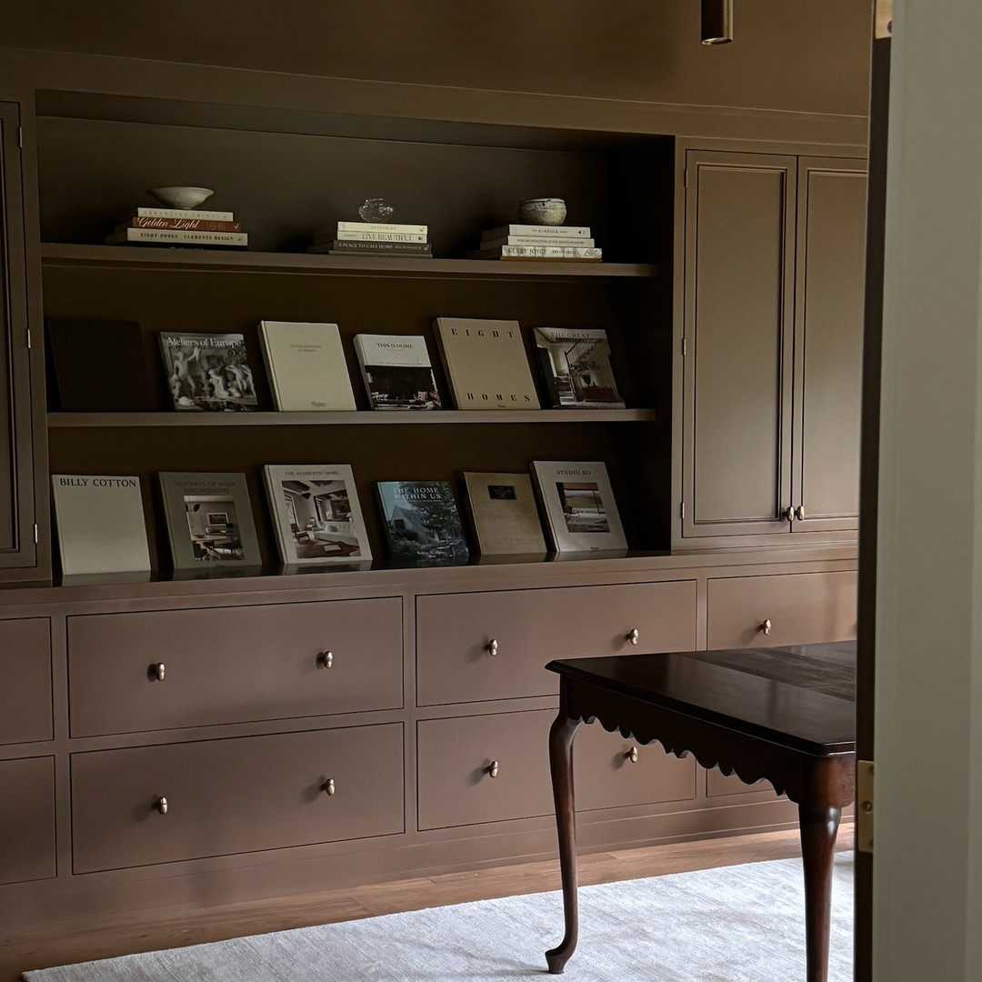 a room with a table, bookshelf and a rug