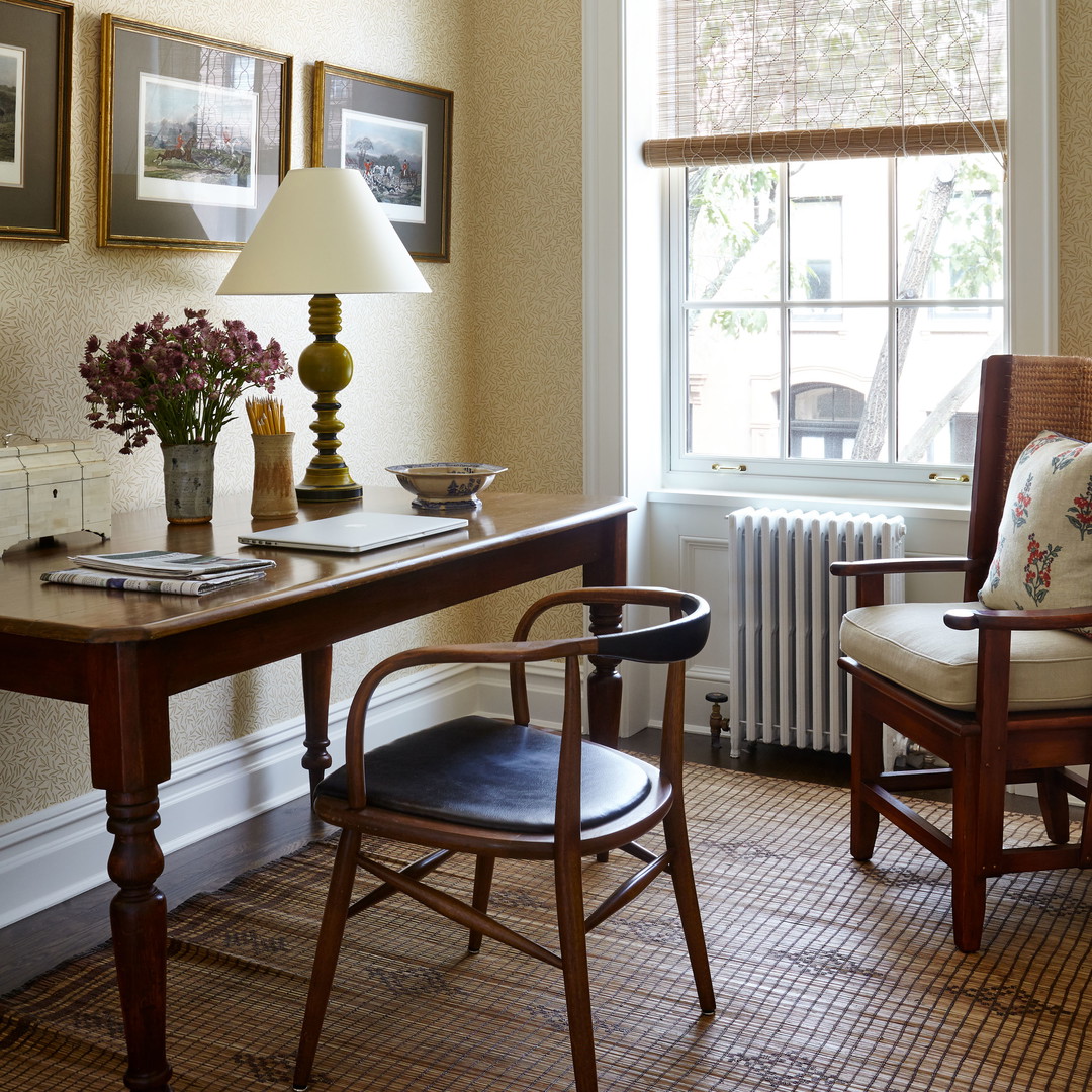 a room with a desk, chair, lamp and pictures on the wall