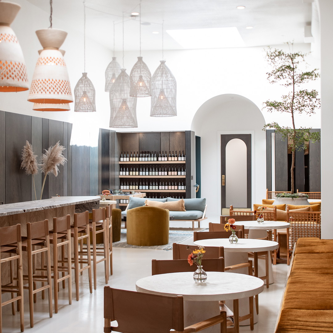 a restaurant with tables, chairs, and bottles of wine