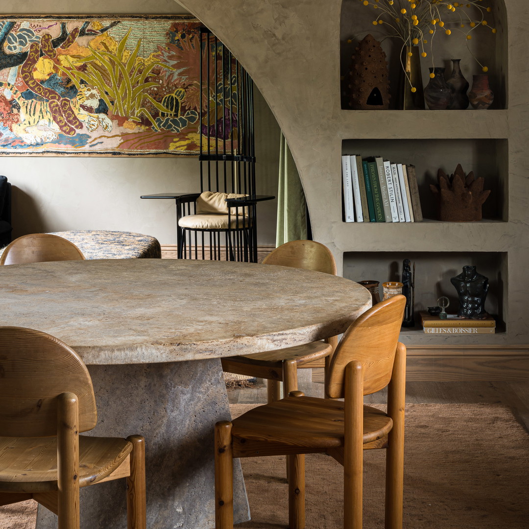 a table and chairs in a room with a painting on the wall