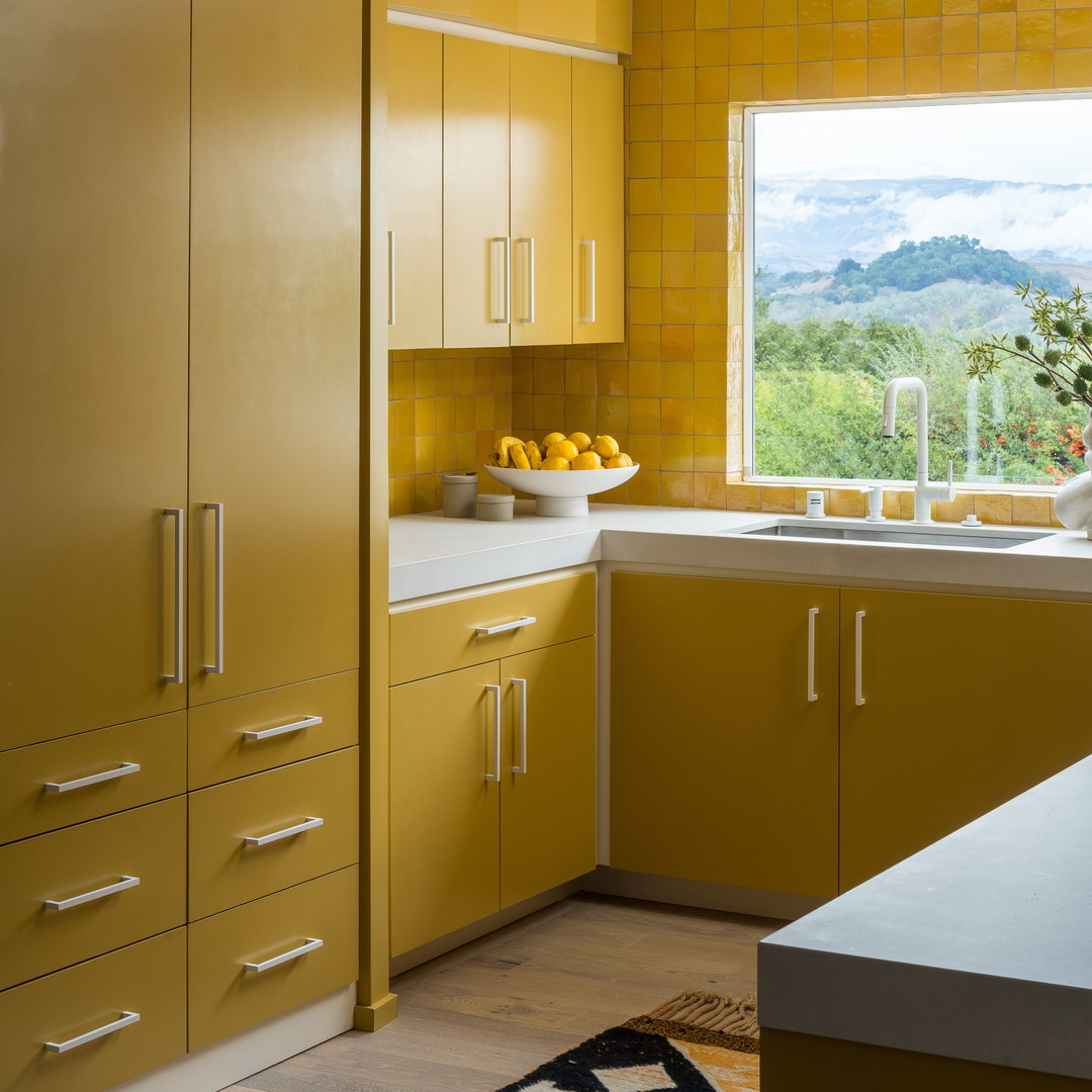 a kitchen with yellow cabinets and a window