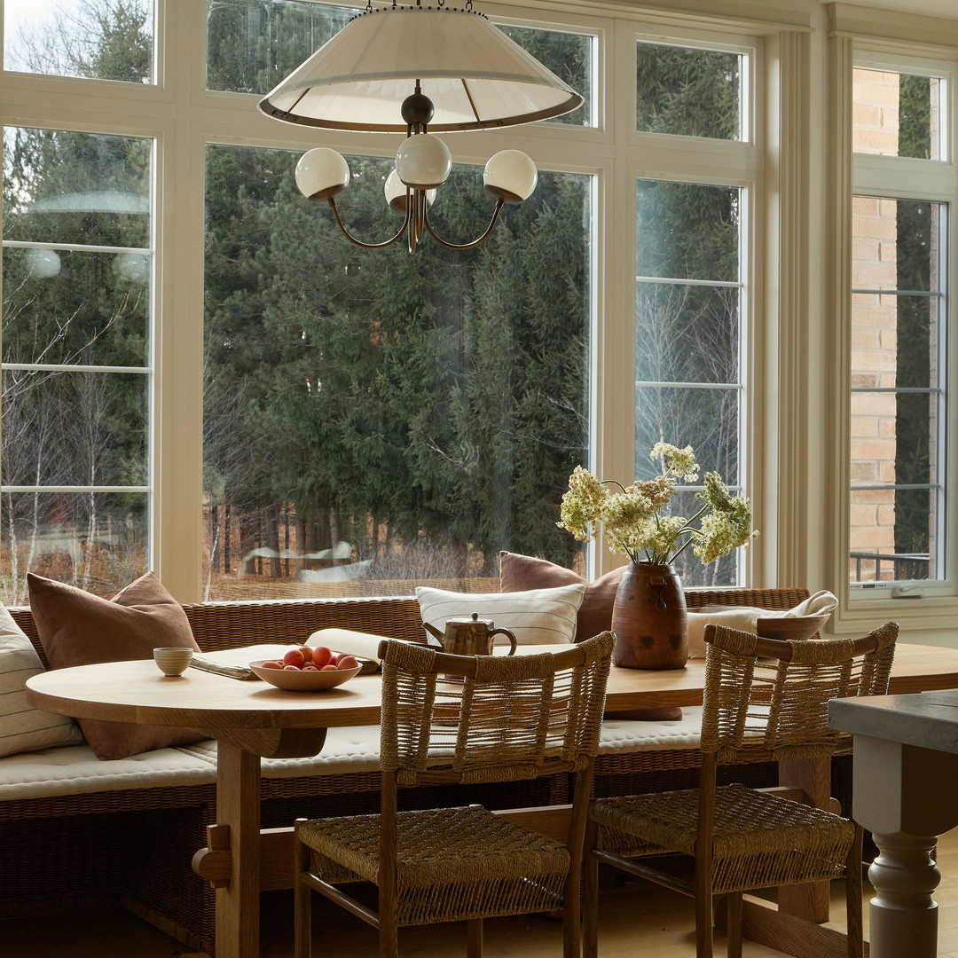 a dining room table with chairs and a bench in front of a large window