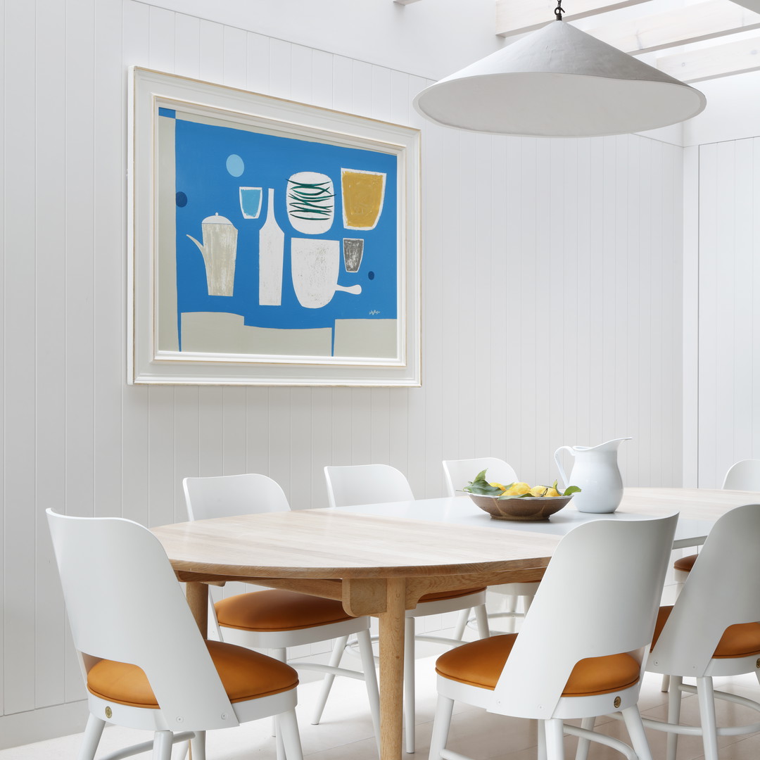 a dining room table with white chairs and a painting on the wall