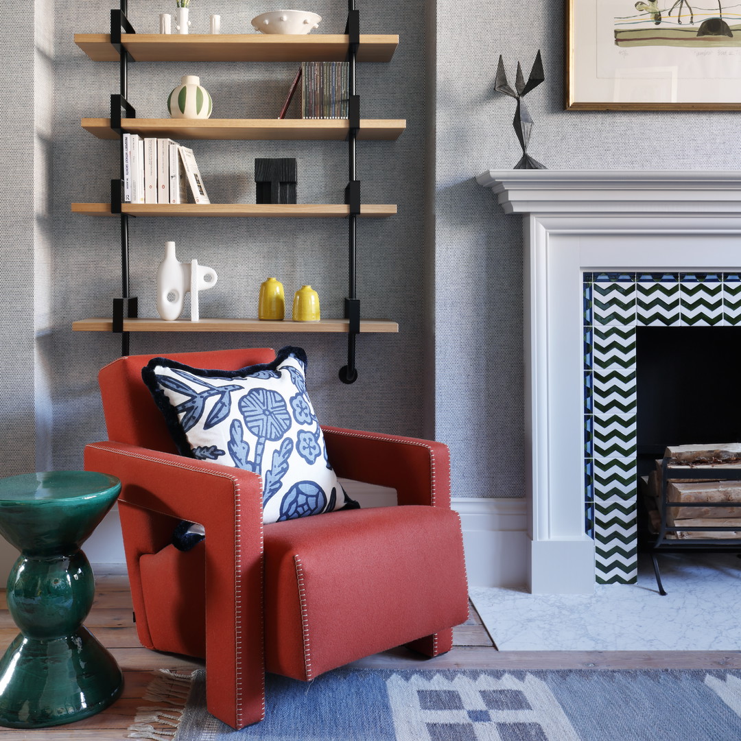 a living room with a red chair and a fire place