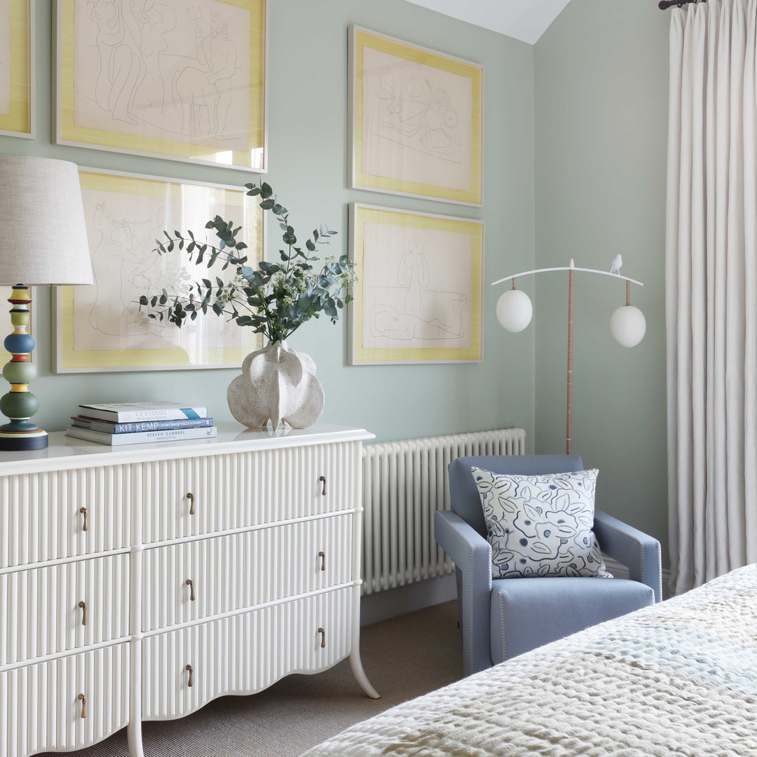 a bedroom with a white dresser and a blue chair