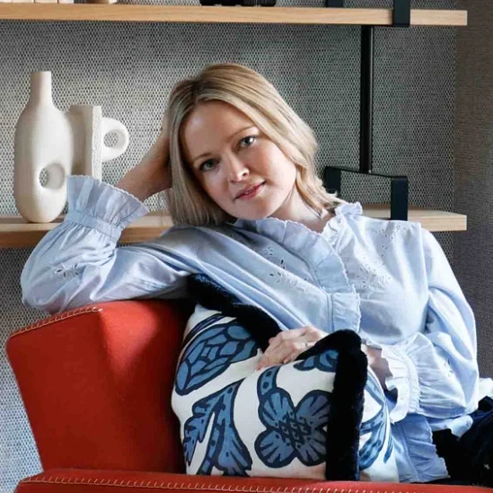 a woman sitting on a red chair in a living room