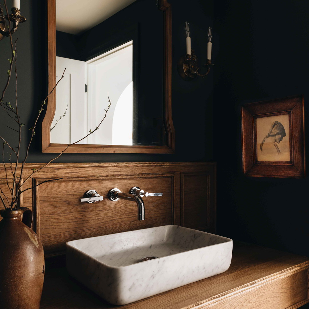 a bathroom sink sitting under a mirror next to a vase