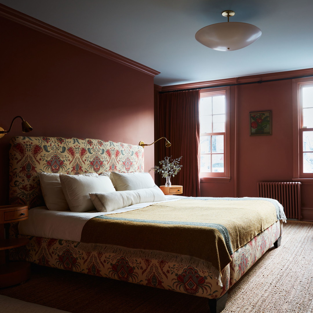 a bedroom with a bed, dresser, and two windows