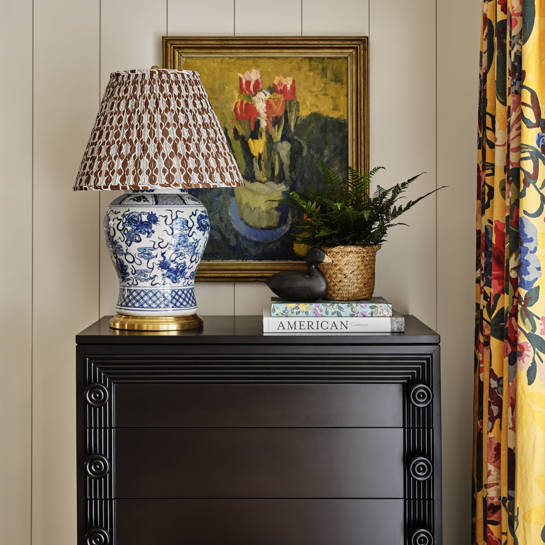 a table with a lamp and a painting on the wall