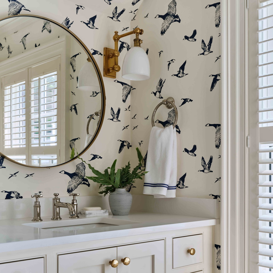 a bathroom with a sink, mirror, and birds wallpaper