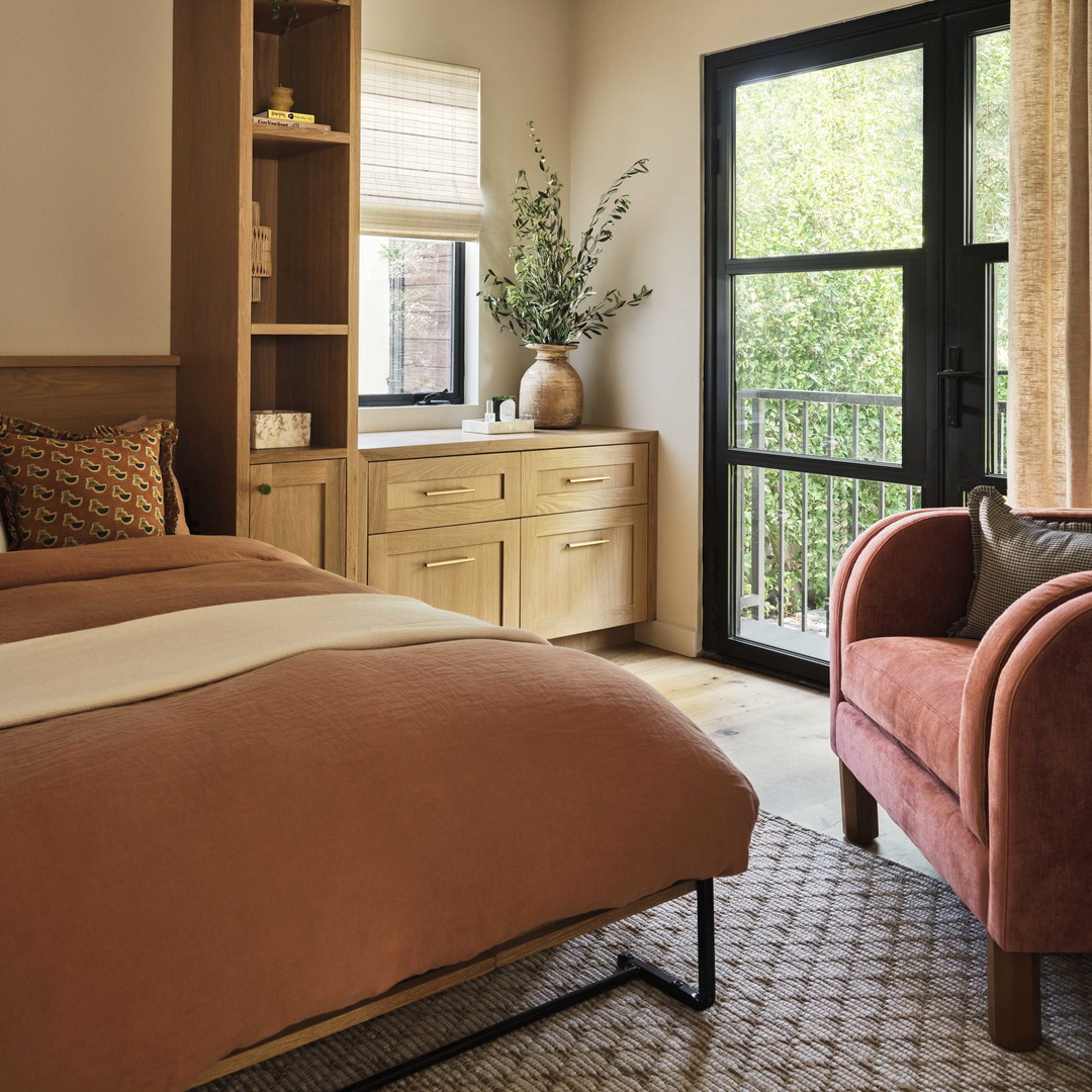 a bedroom with a bed, chair, dresser and window