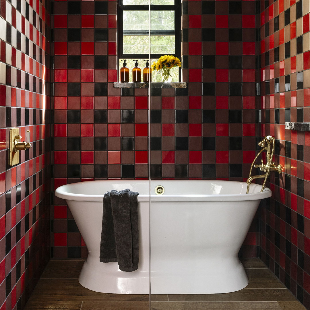 a bathroom with red and black tiles on the walls