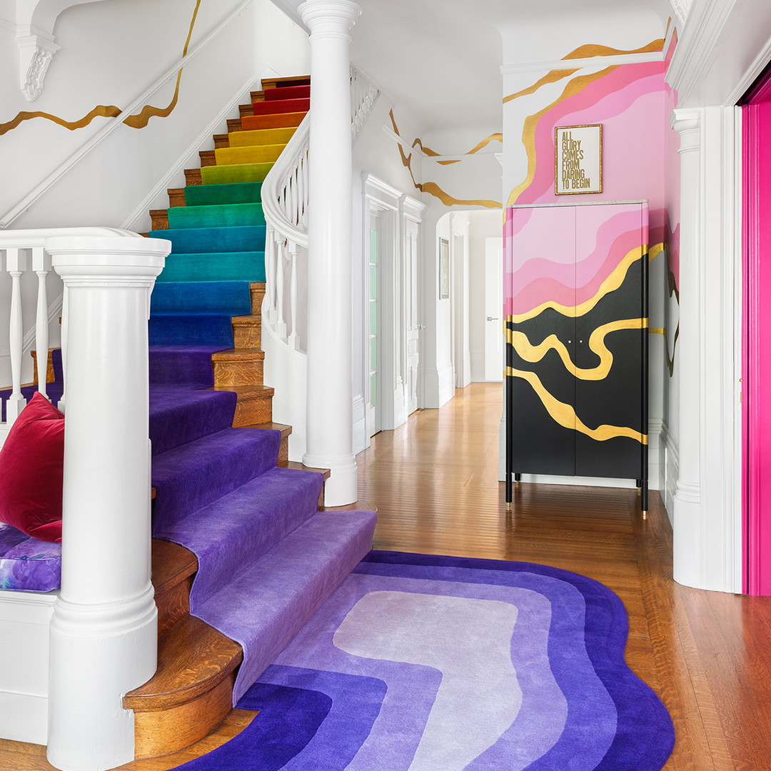 a room with a staircase and a colorful rug