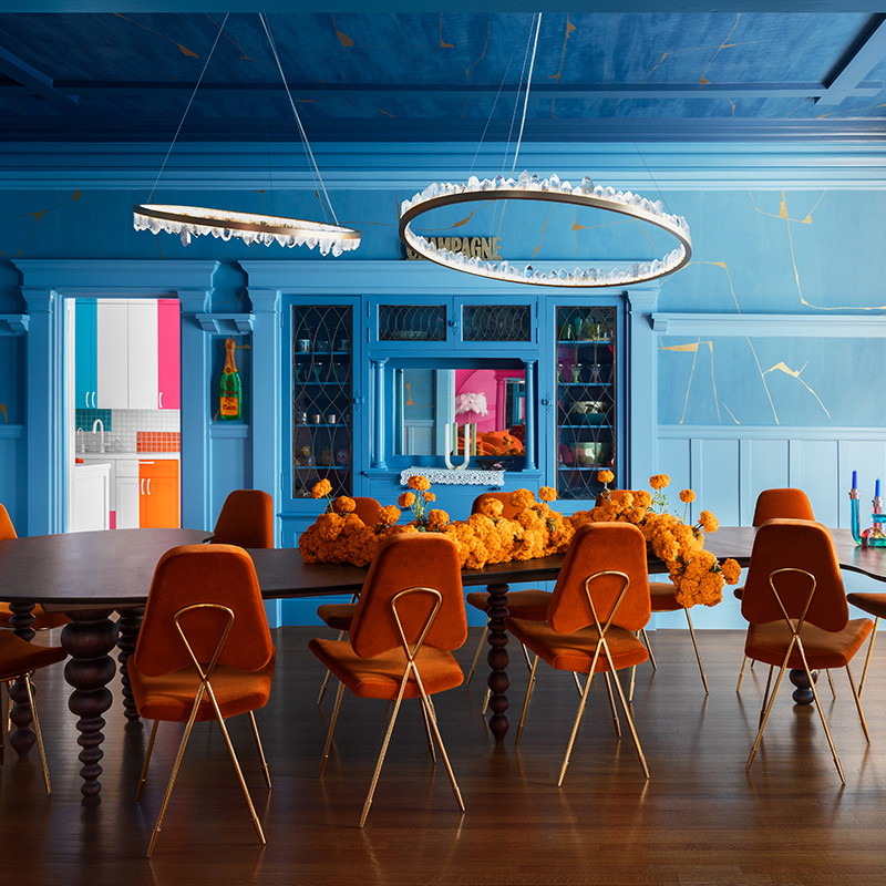 a dining room with blue walls and orange chairs