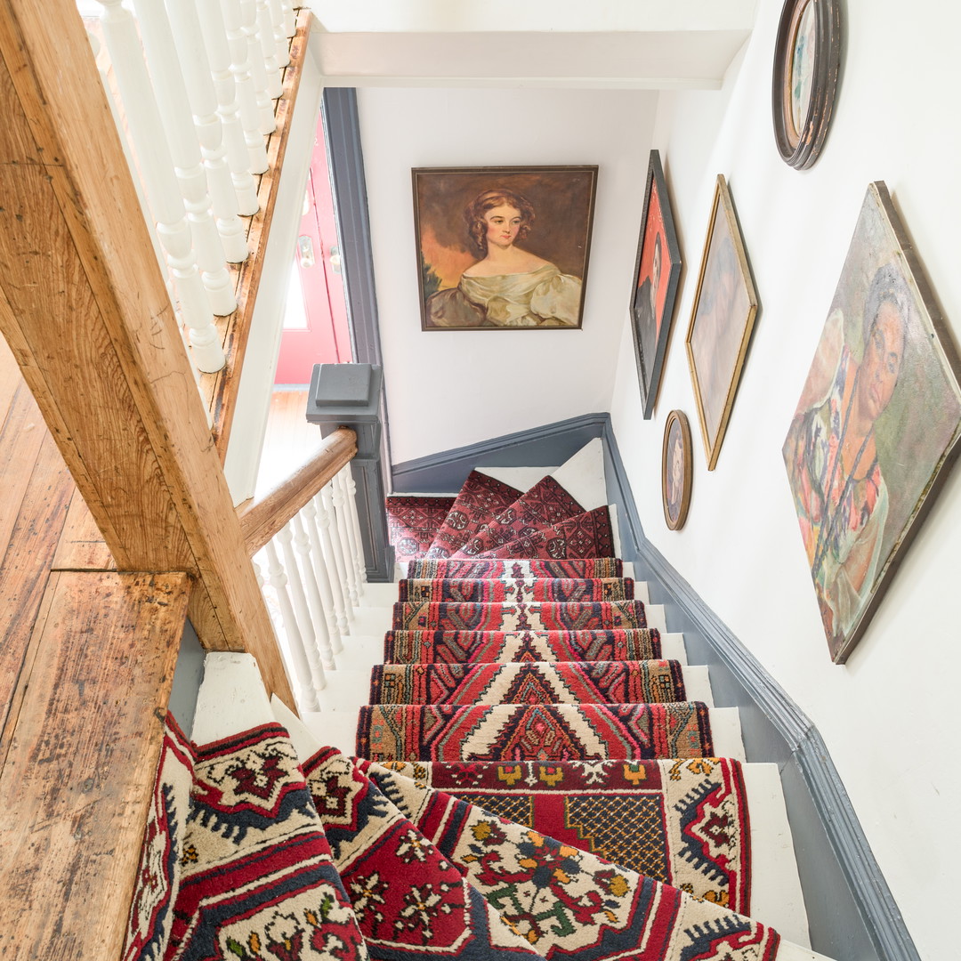 a stair case with rugs and pictures on the wall