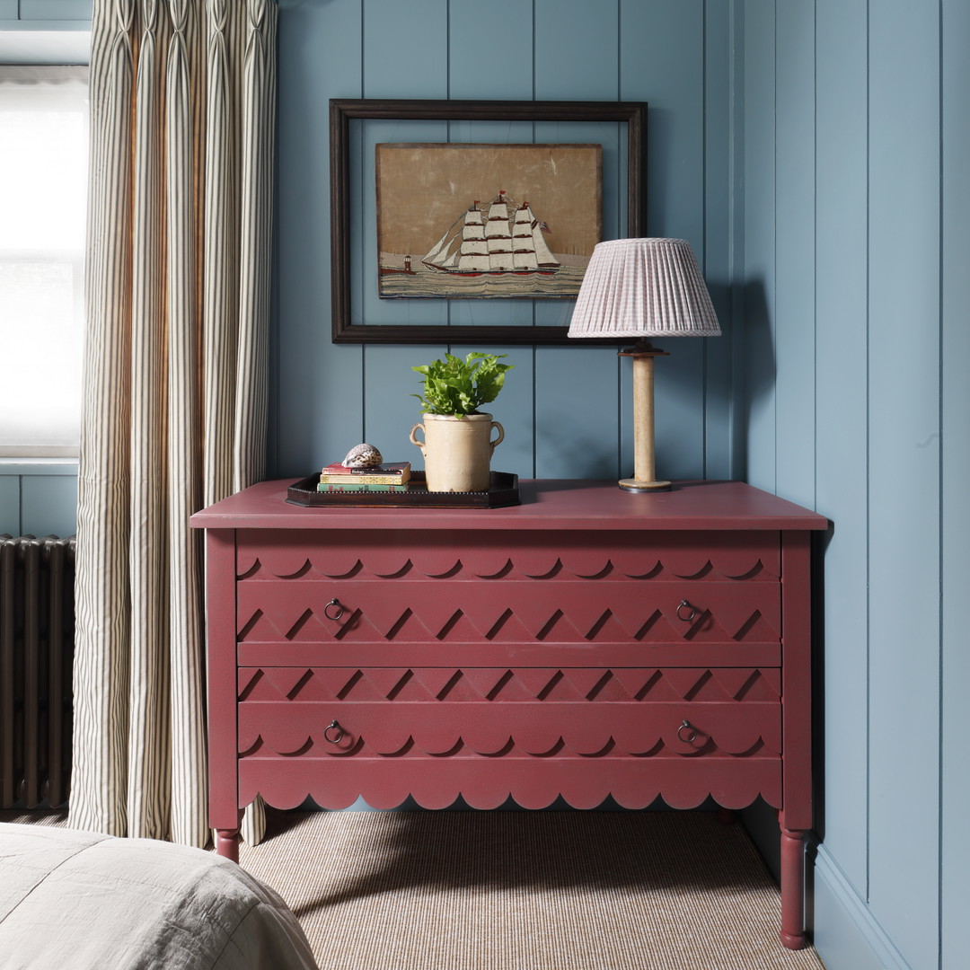 a bedroom with blue walls and a red dresser