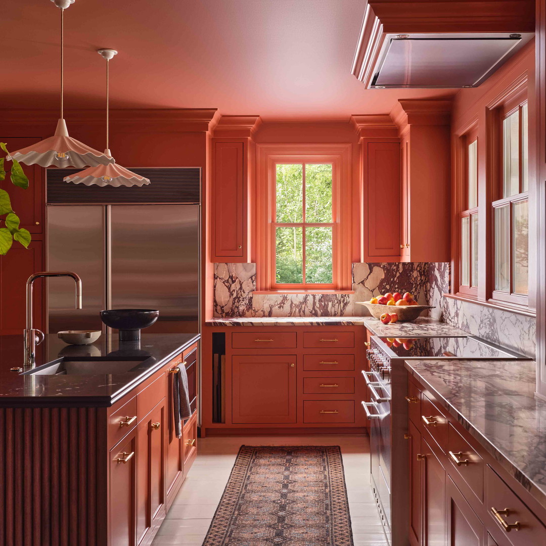 a kitchen with red cabinets and marble counter tops