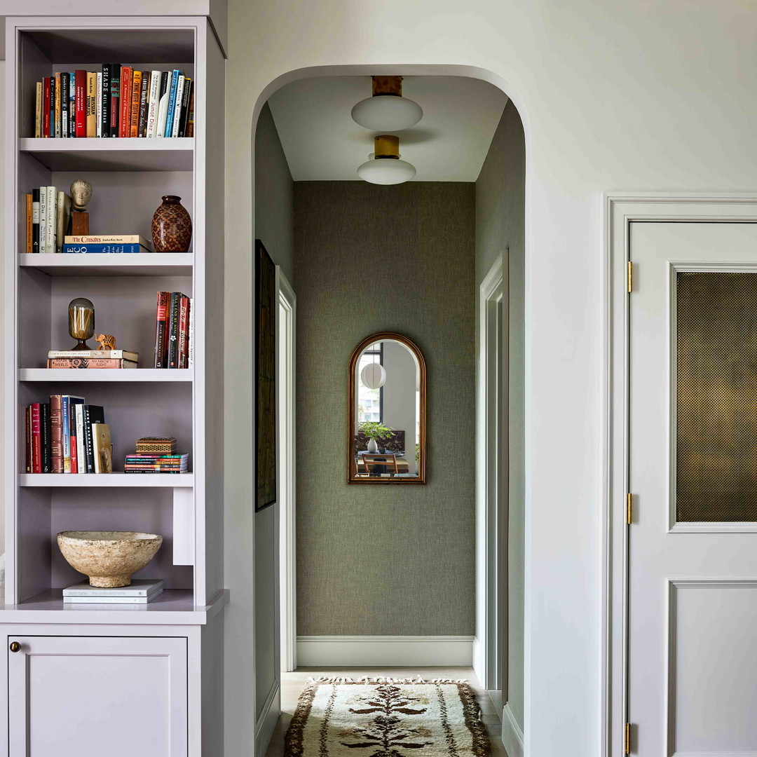 a living room with a couch a book shelf and a mirror