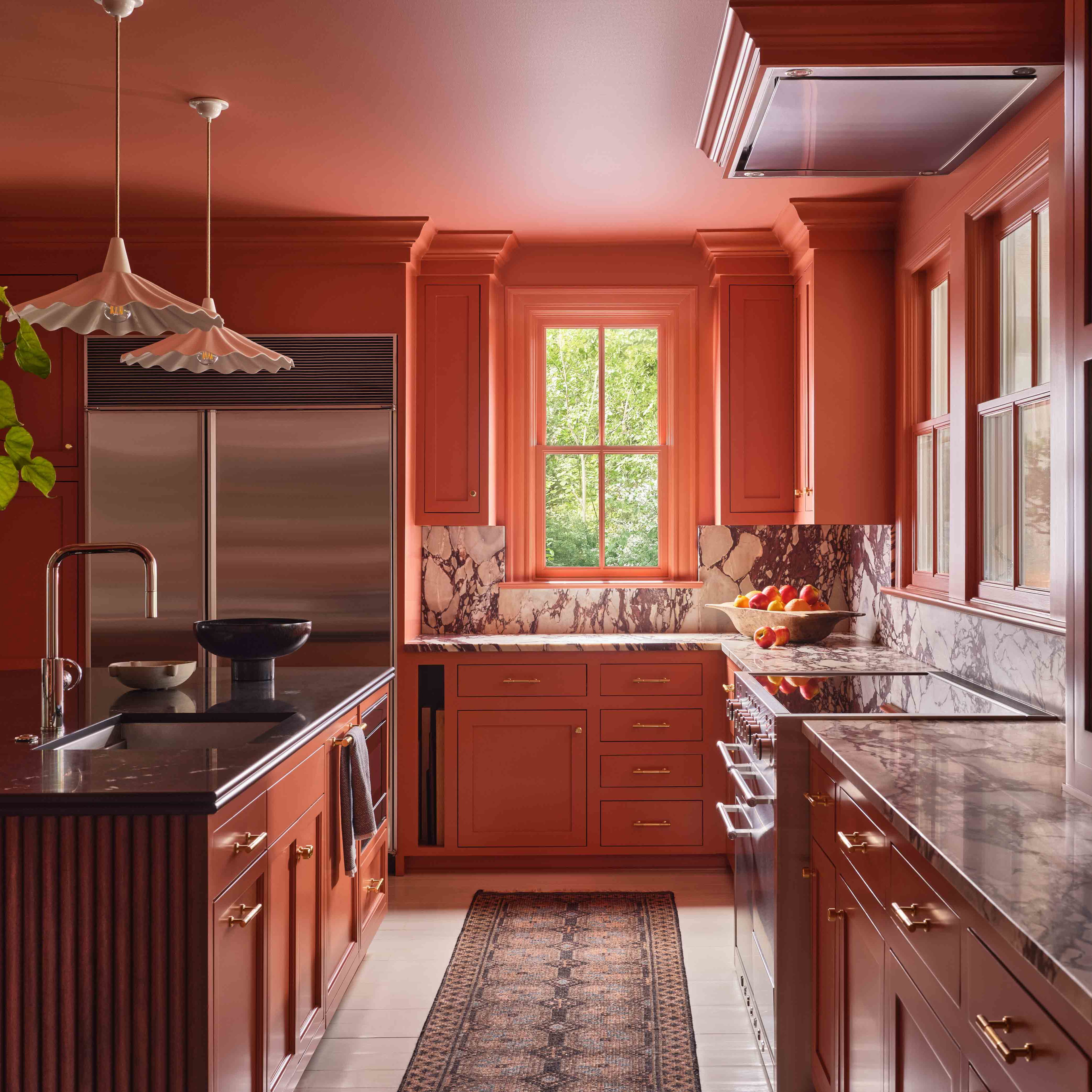 a kitchen with red cabinets and marble counter tops