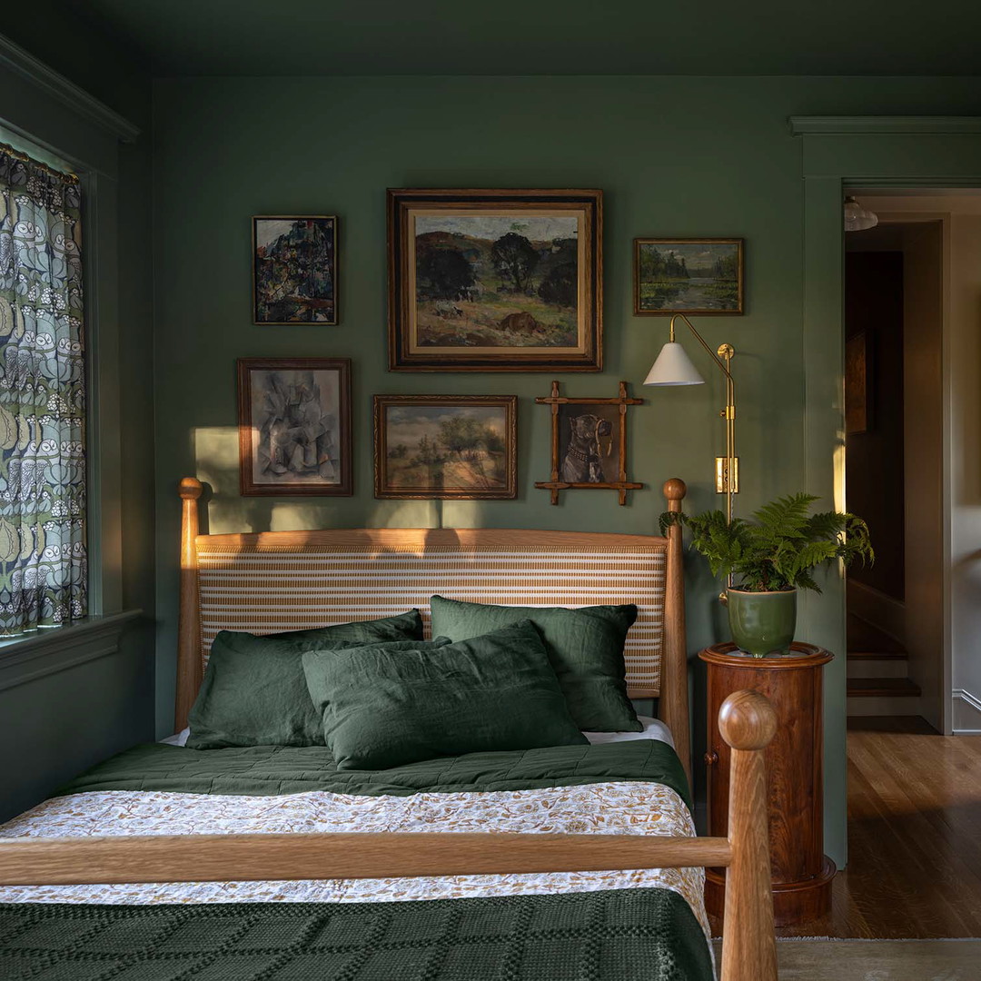 a bedroom with green walls and pictures on the wall