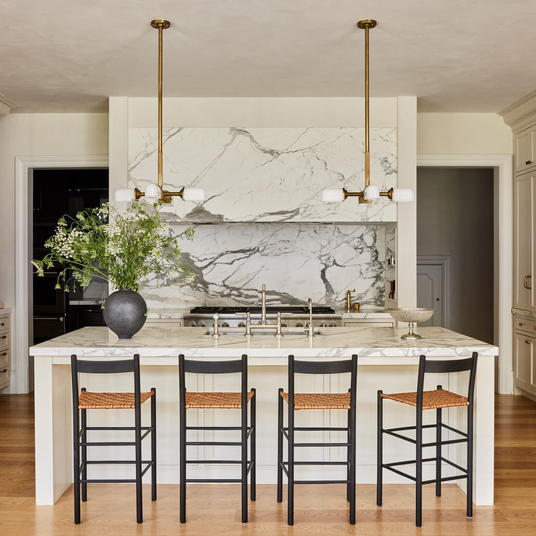 a large kitchen with a marble island and bar stools