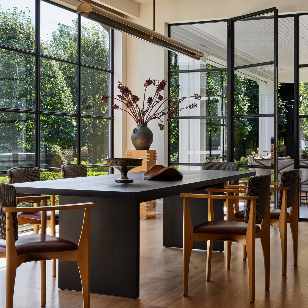 a dining room table with chairs and a vase of flowers