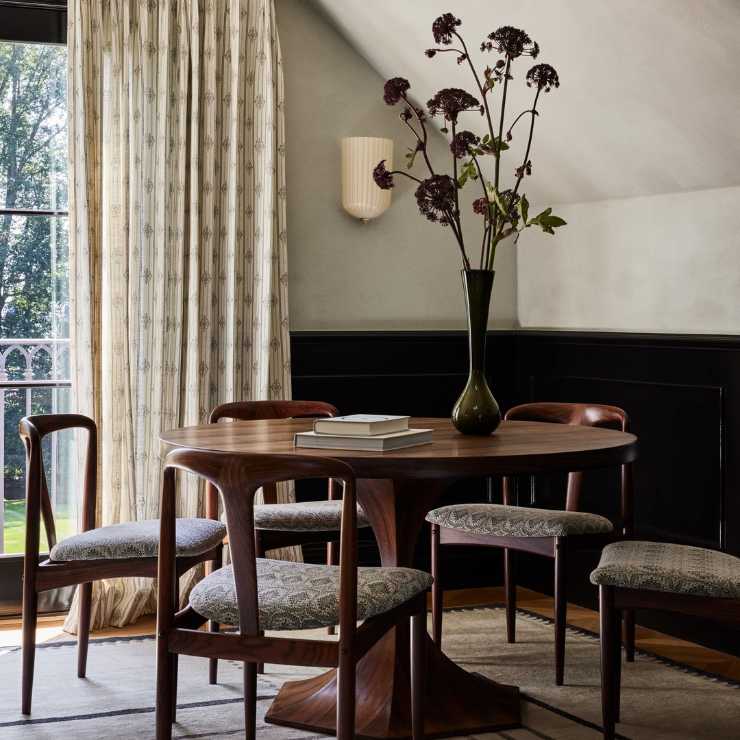 a room with a table, chairs and a vase of flowers