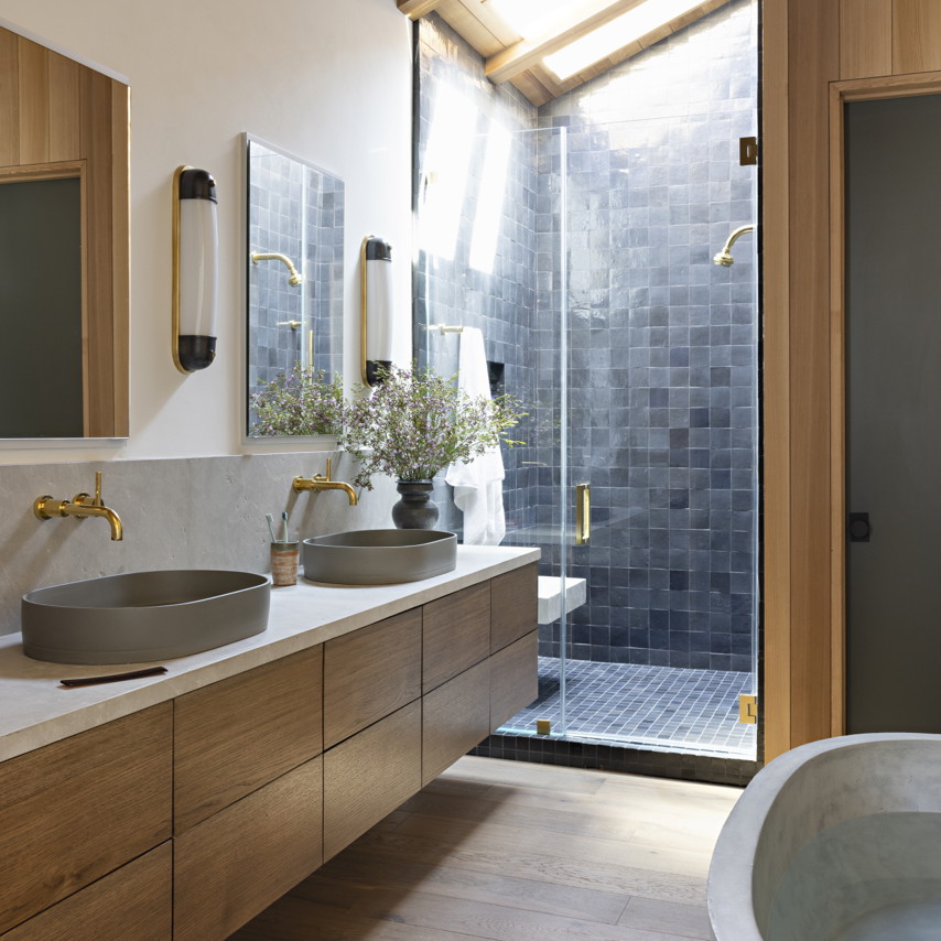 a bathroom with two sinks and a walk in shower