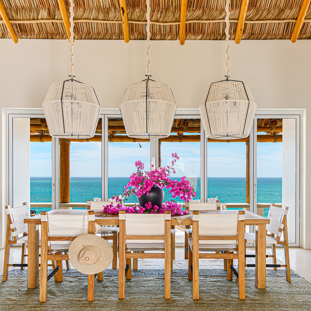 a dining room with a table and chairs and a view of the ocean