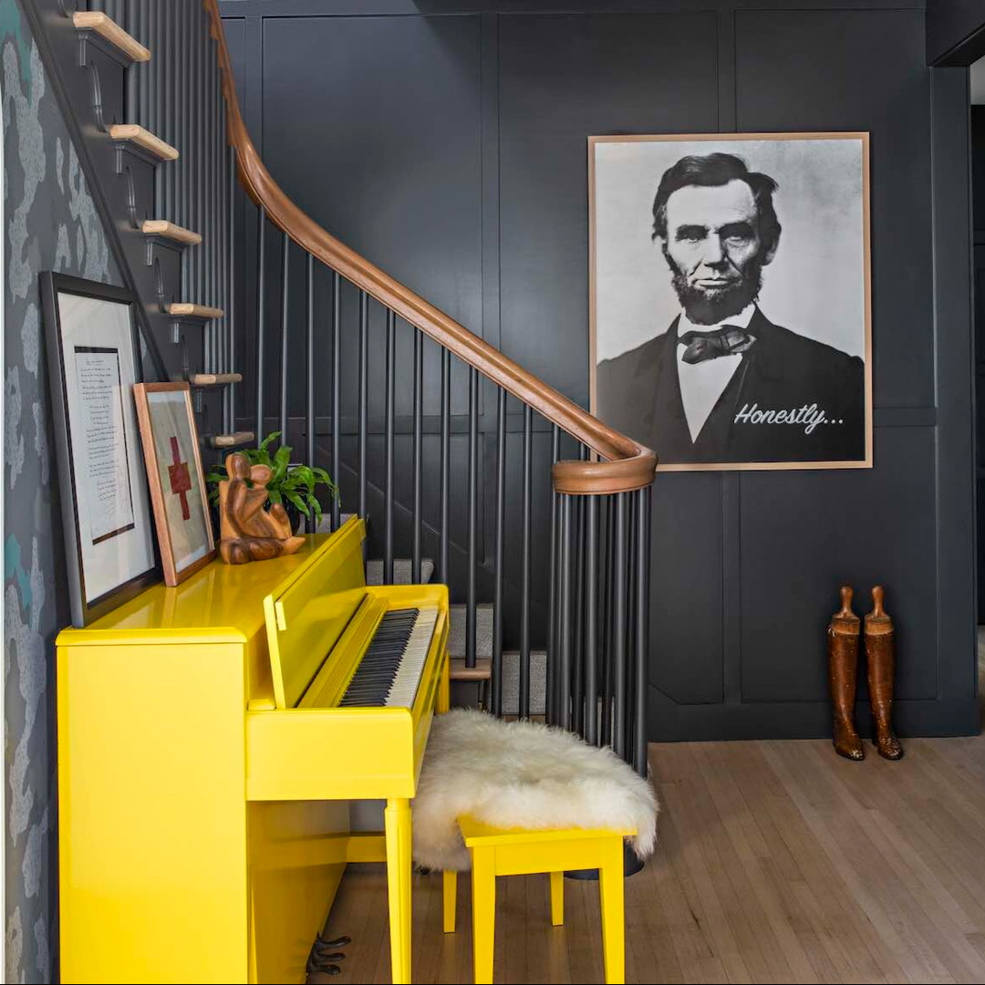 a staircase with a yellow piano and a picture on the wall