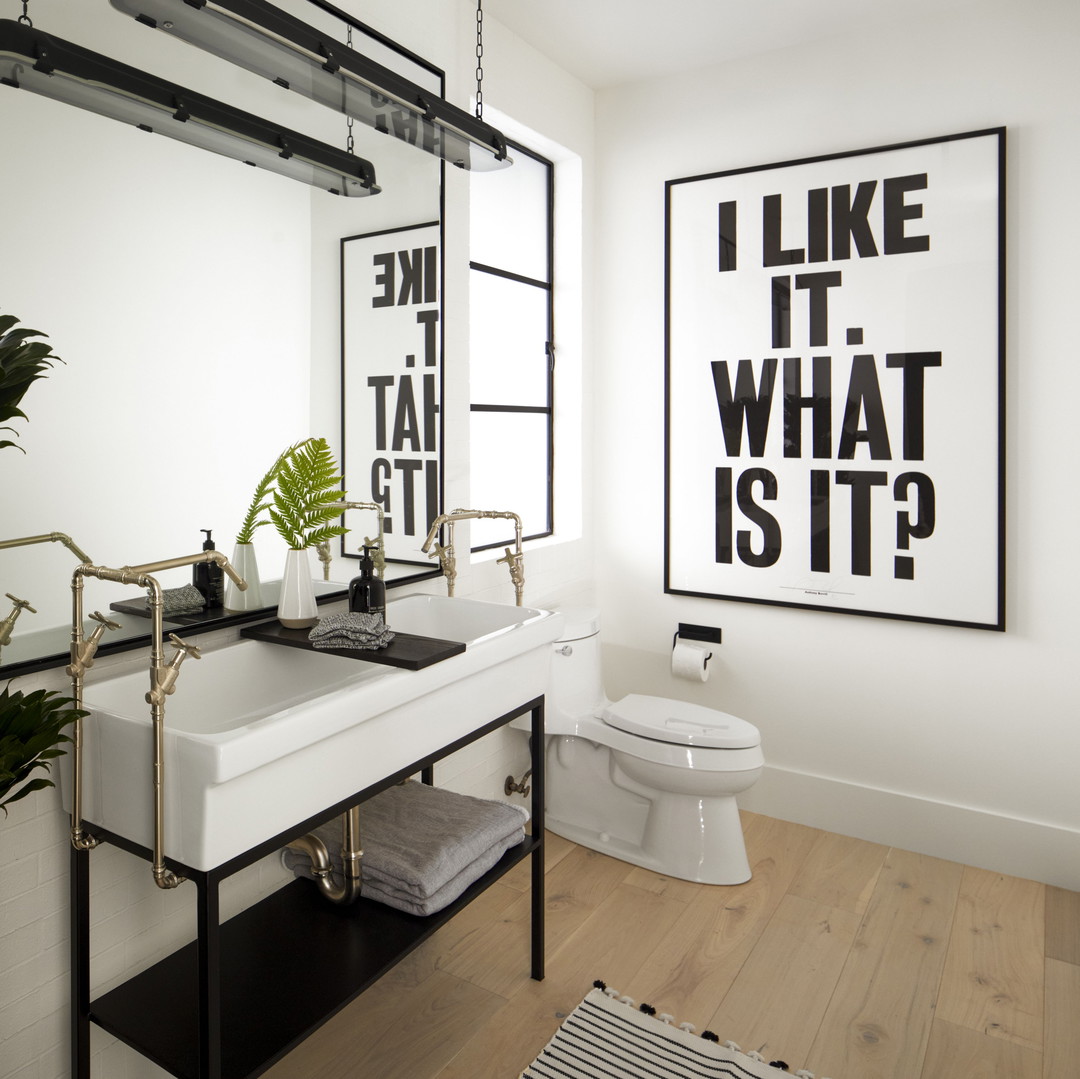 a bathroom with a sink, toilet, mirror and a plant