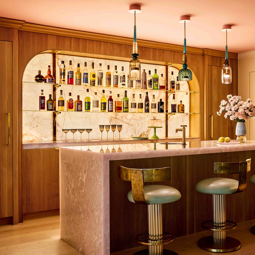 a bar with stools and bottles on the wall