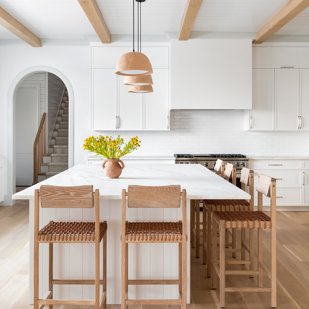 a kitchen with a center island and wooden chairs