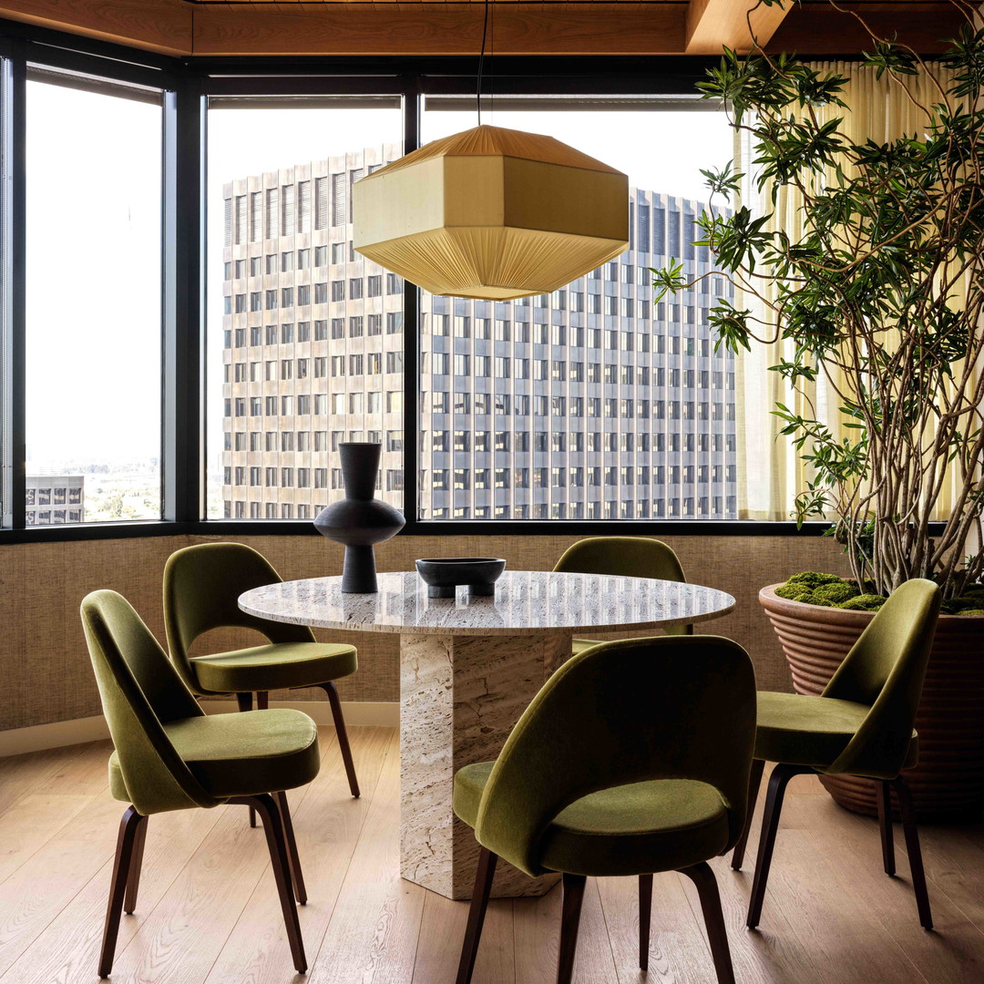 a dining room with a round table surrounded by green chairs