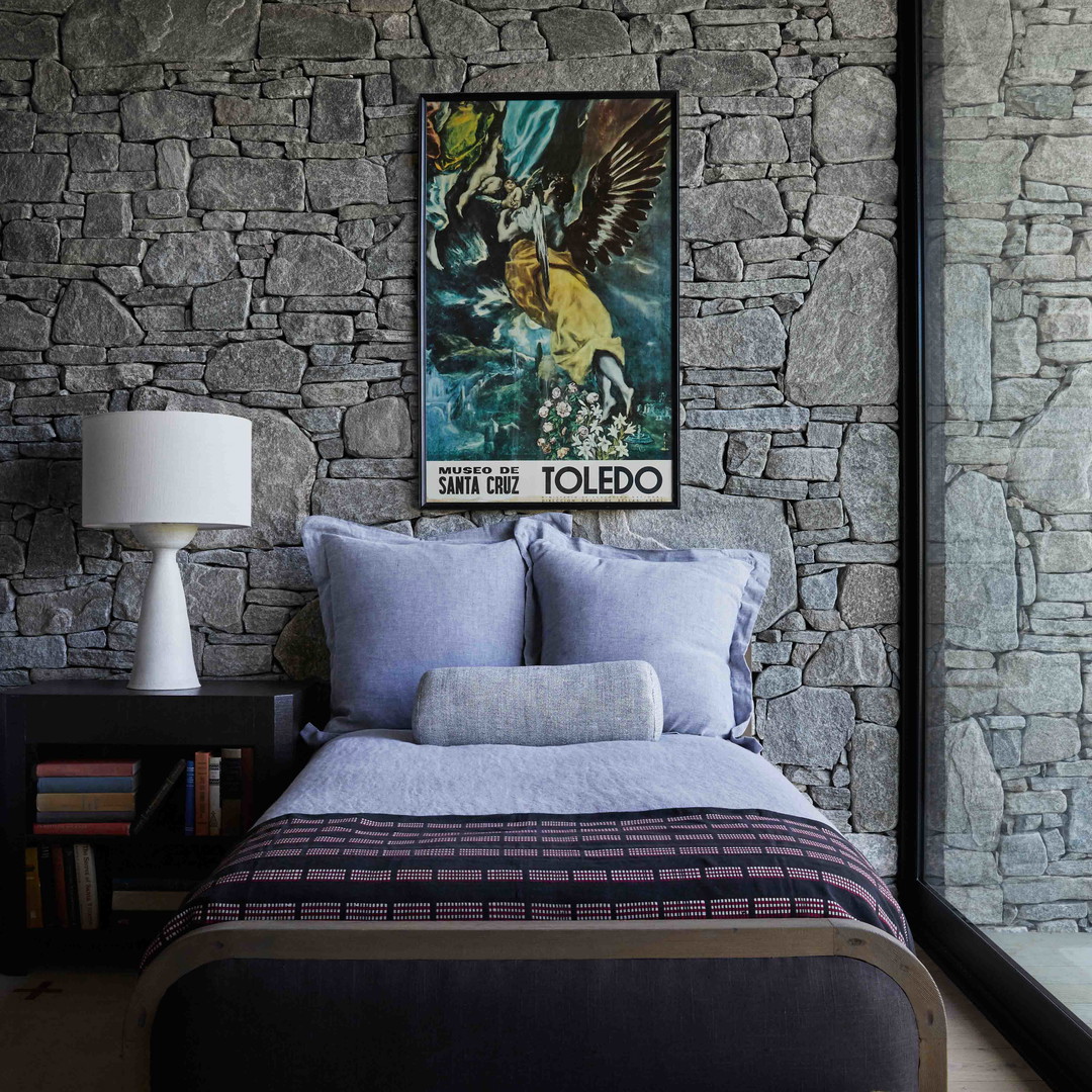 a bedroom with a stone wall and a painting on the wall