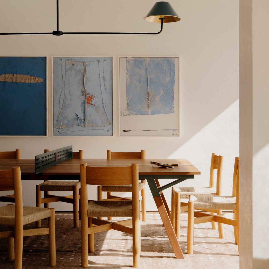 a room with a table and chairs and paintings on the wall